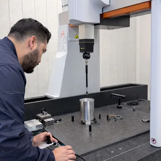 Quality assurance inspector running a dimensional check on a Mitutoyo Crysta-Apex S CNC CMM machine.